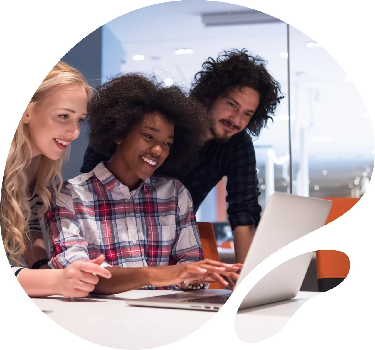 Three colleagues reviewing work together at a laptop